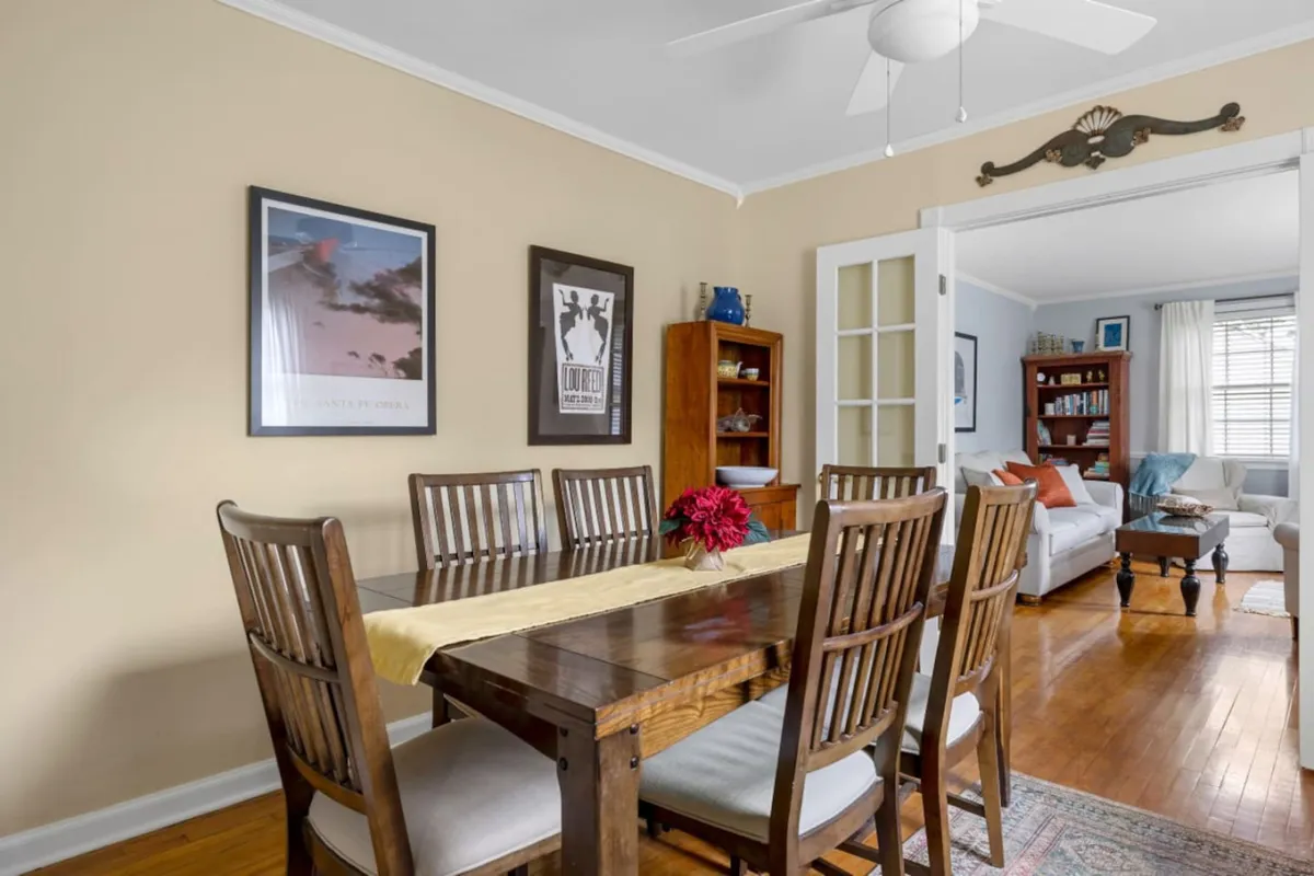 The dining area features a spacious table set for meals or games, surrounded by decorative wall art and a well-stocked bookshelf, evoking a sense of warmth and community. The arrangement hints at memorable family dinners, friendly game nights, and celebratory gatherings.