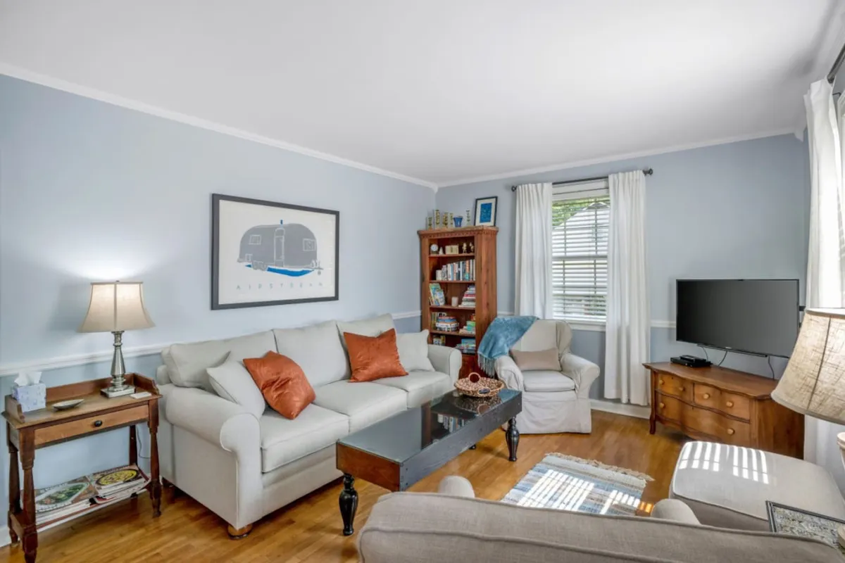 This image showcases a cozy living space centered around a comfortable sofa adorned with decorative pillows, a coffee table set for relaxation or conversation, and a bookshelf filled with books. The overall mood is warm and inviting, with hints of socializing and leisure activities like reading or watching television.
